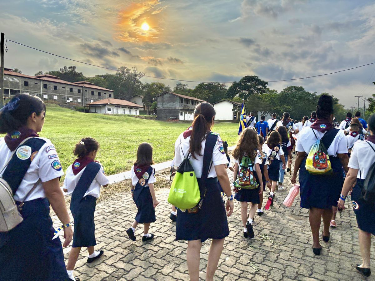 Aventureiros e diretoria caminhando de uniforme de gala ao amanhecer